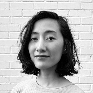 Home black and white headshot of a woman with olive skin and chin-length brown wavy hair